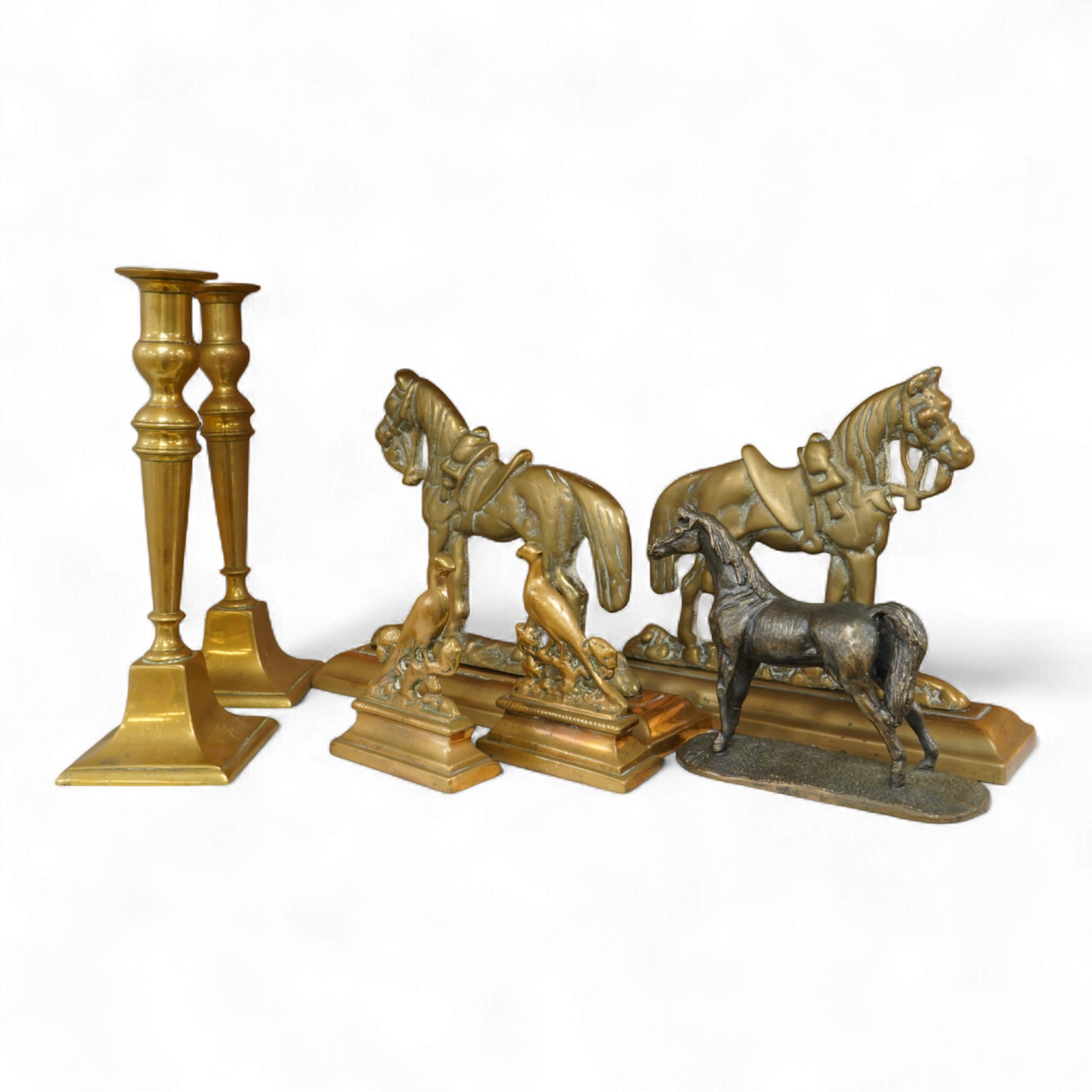A bronze figure of a horse, two pairs of brass doorstops and a similar pair of candlesticks, 25cm